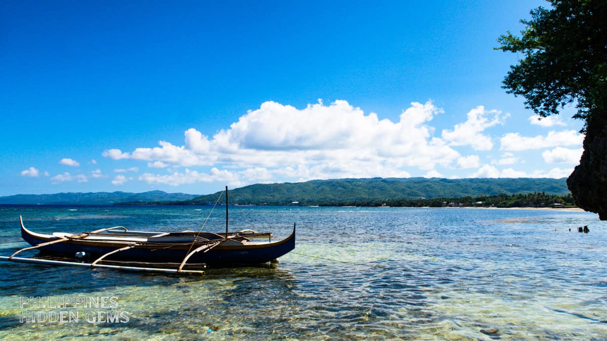 A boat floating on the crystal-clear waters on a sunny day.