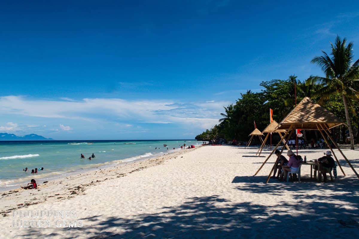 Anda Beach with small native parasols on a sunny day.
