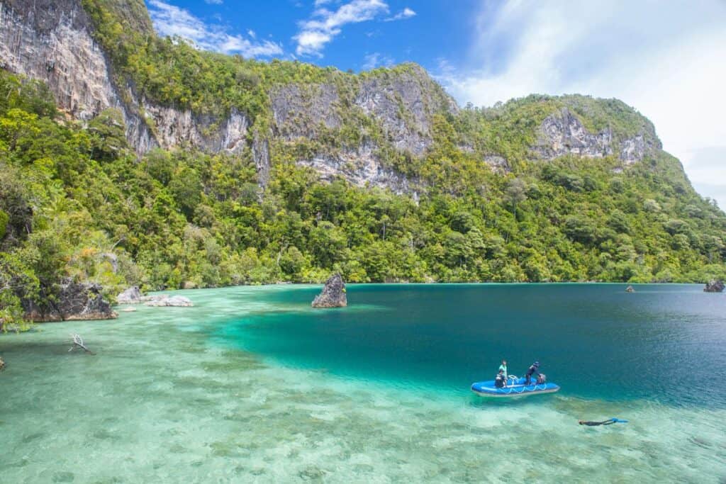 A boat is floating in the clear water of a tropical island.