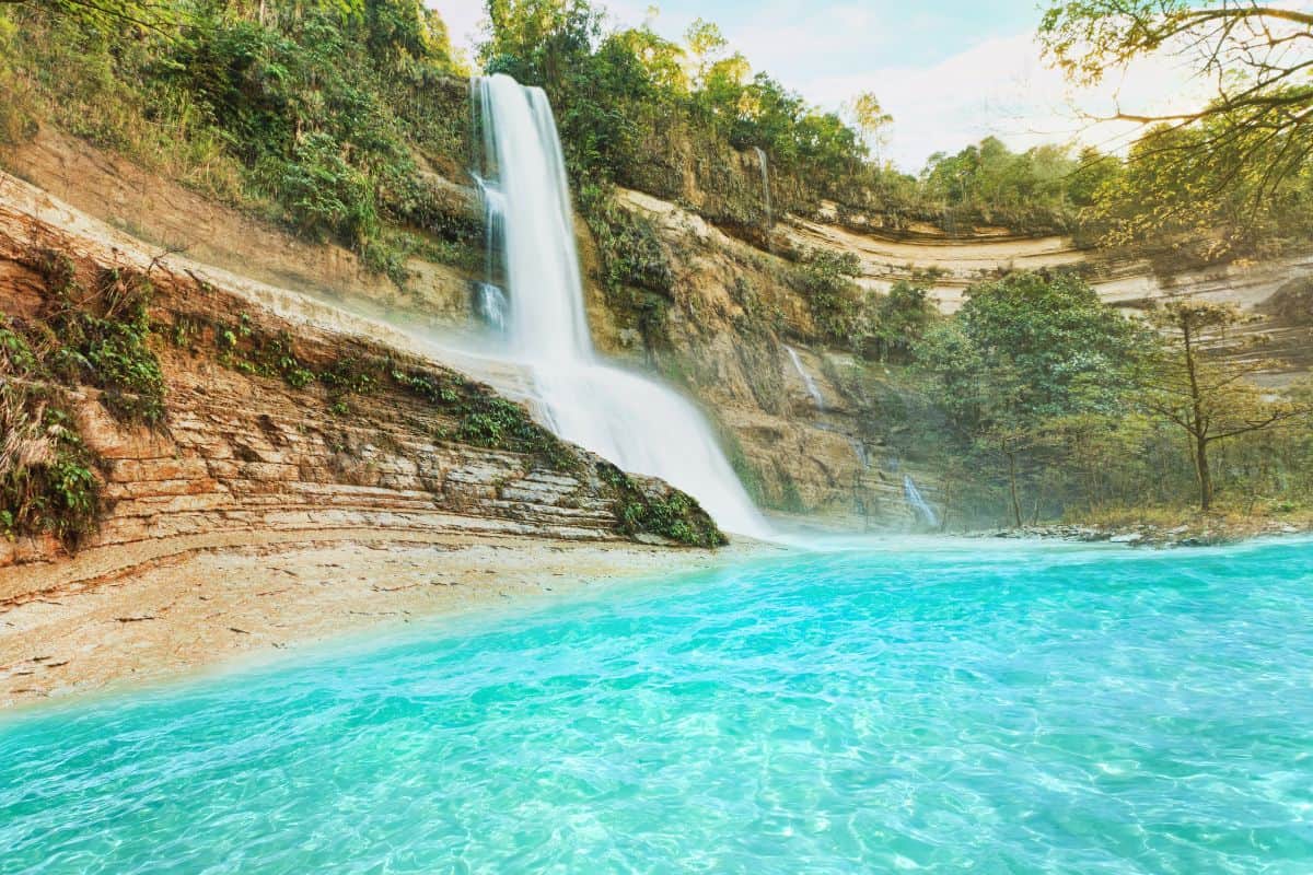 Aerial view of Can-Umantad Falls cascading into turquoise pools surrounded by lush green forest in Bohol, Philippines.