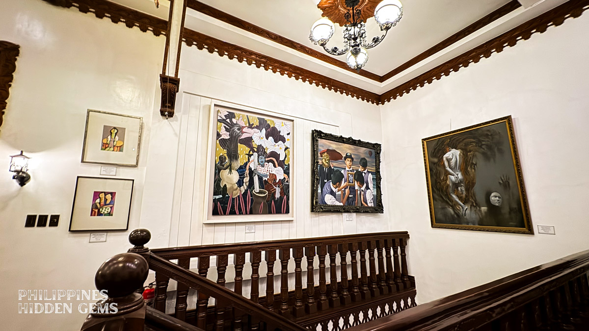 Staircase area of an old Spanish mansion with paintings.