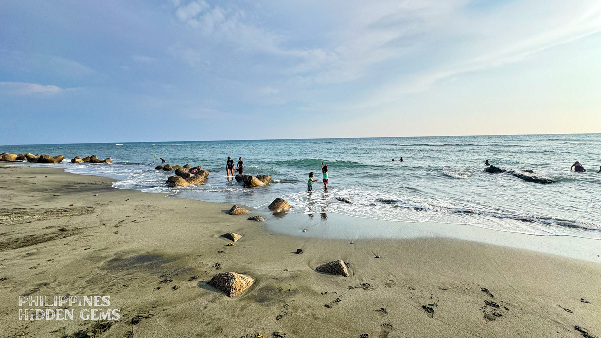 Kids swimming in the sea and playing on a black-sand beach.