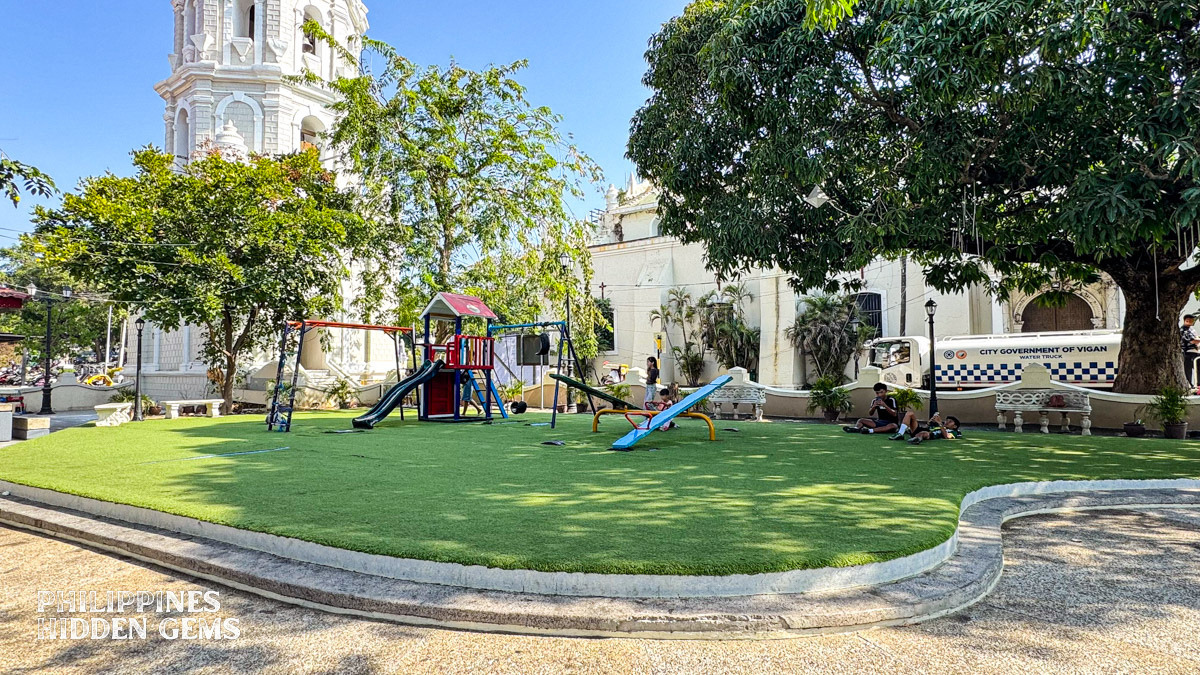 A playground shaded by trees at a plaza in Vigan.