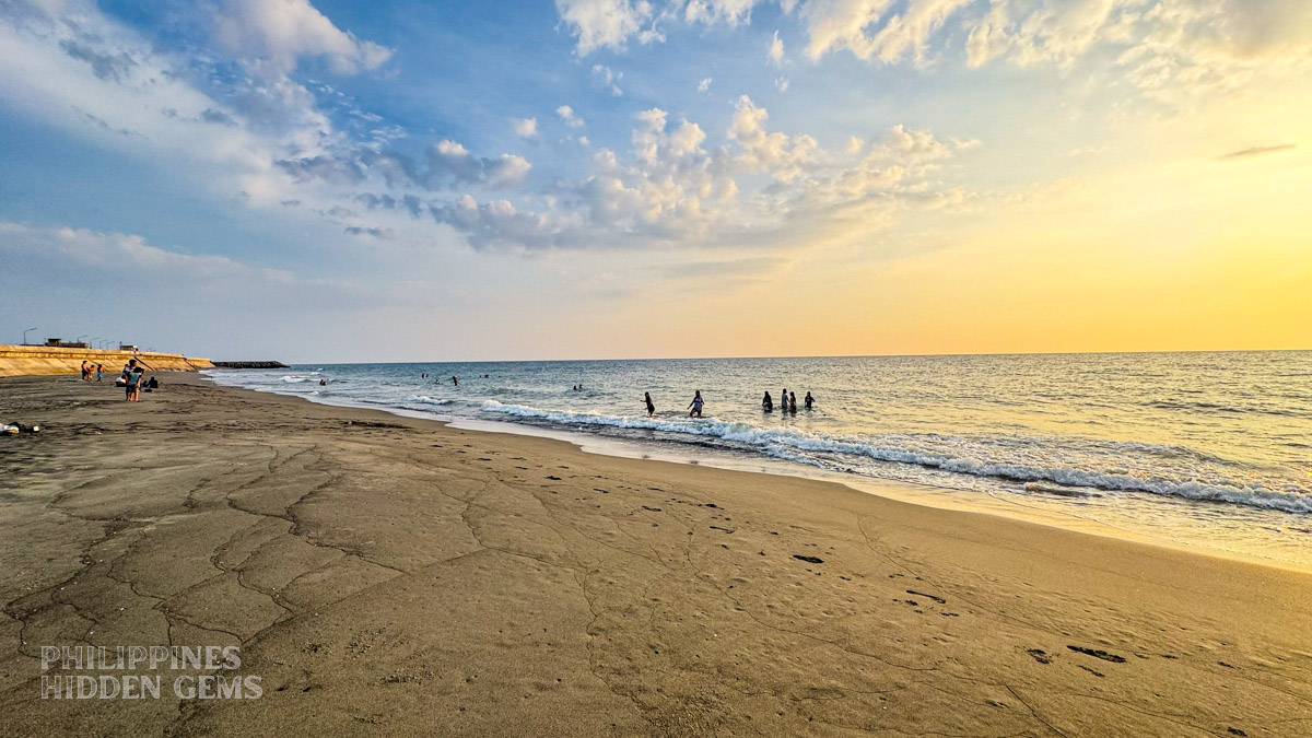 People playing on the beach at sunset.
