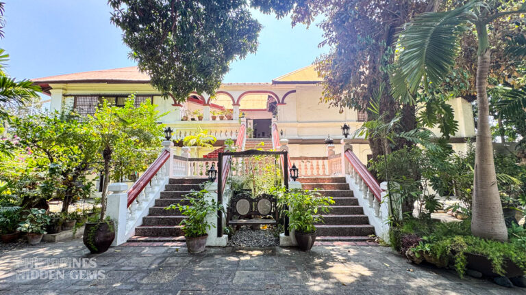 Where to stay in Vigan: staircase of an old Spanish colonial house surrounded by trees, in the Philippines.