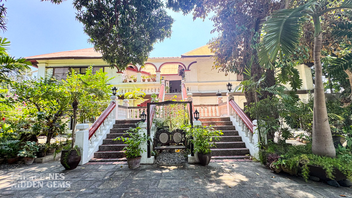 Where to stay in Vigan: staircase of an old Spanish colonial house surrounded by trees, in the Philippines.