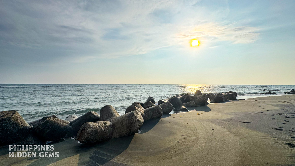 Beach with jackstone-shaped concrete breakwaters at sunset.
