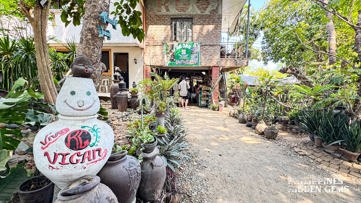 The garden entrance to a pottery workshop with pottery pieces and plants.