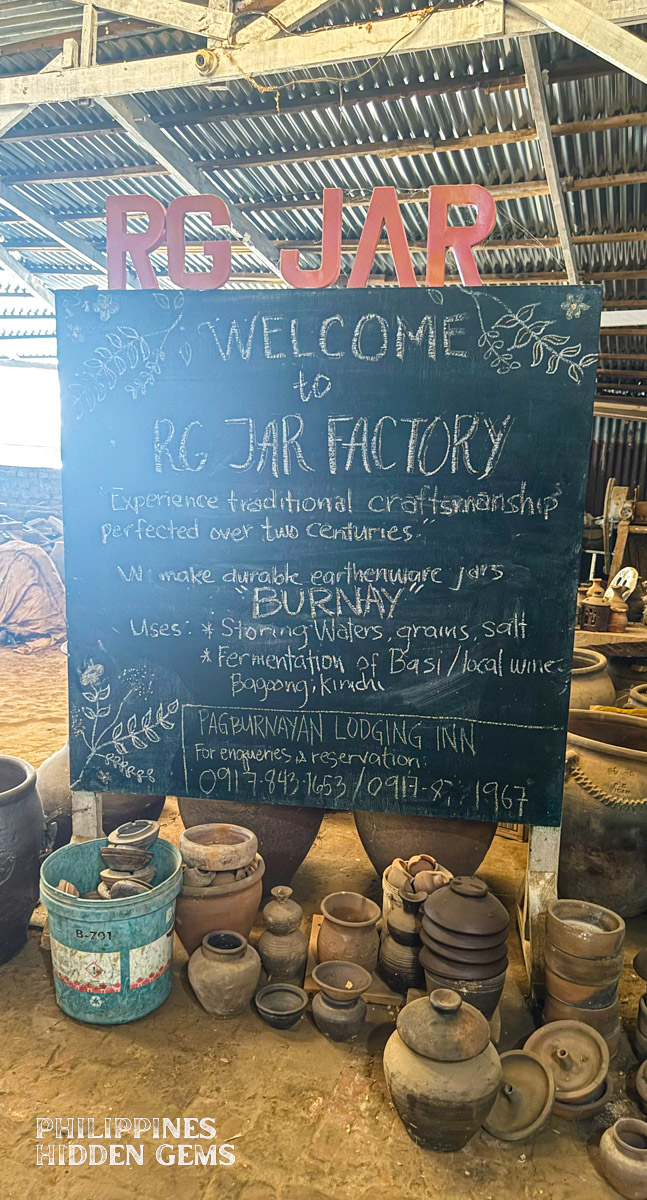 A chalk board standing between pottery pieces.
